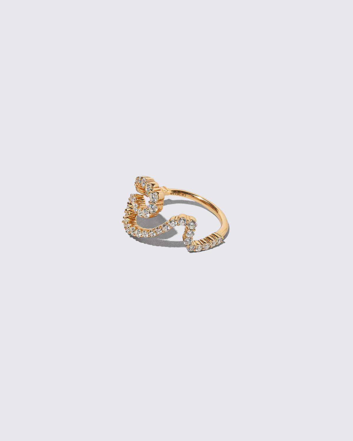View from the side of the Gold White Diamond Tsunami Ring on light color background.