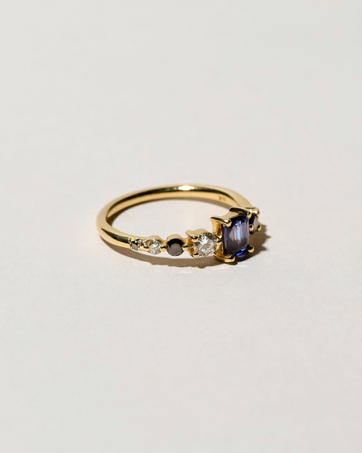 View from the side of the Sapphire Seven Sisters Ring on light color background.