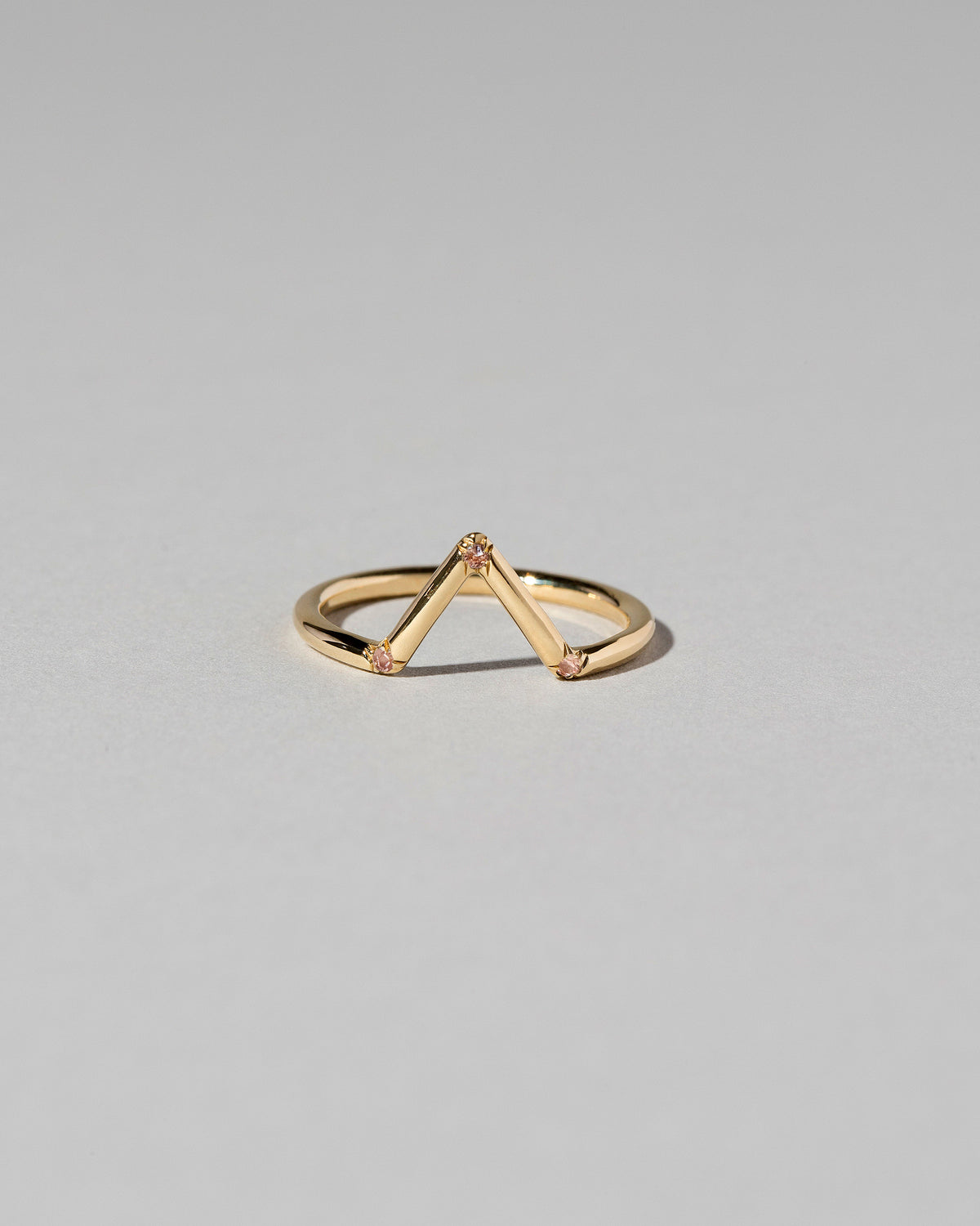 Gold Peach Sapphire Three Stone Triangle Band on light color background.