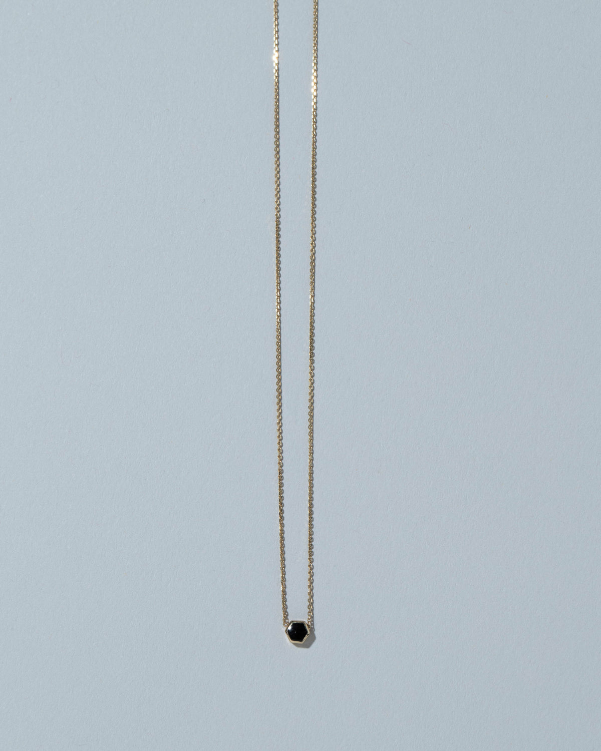 Black Spinel Hexagon Necklace on light color background.