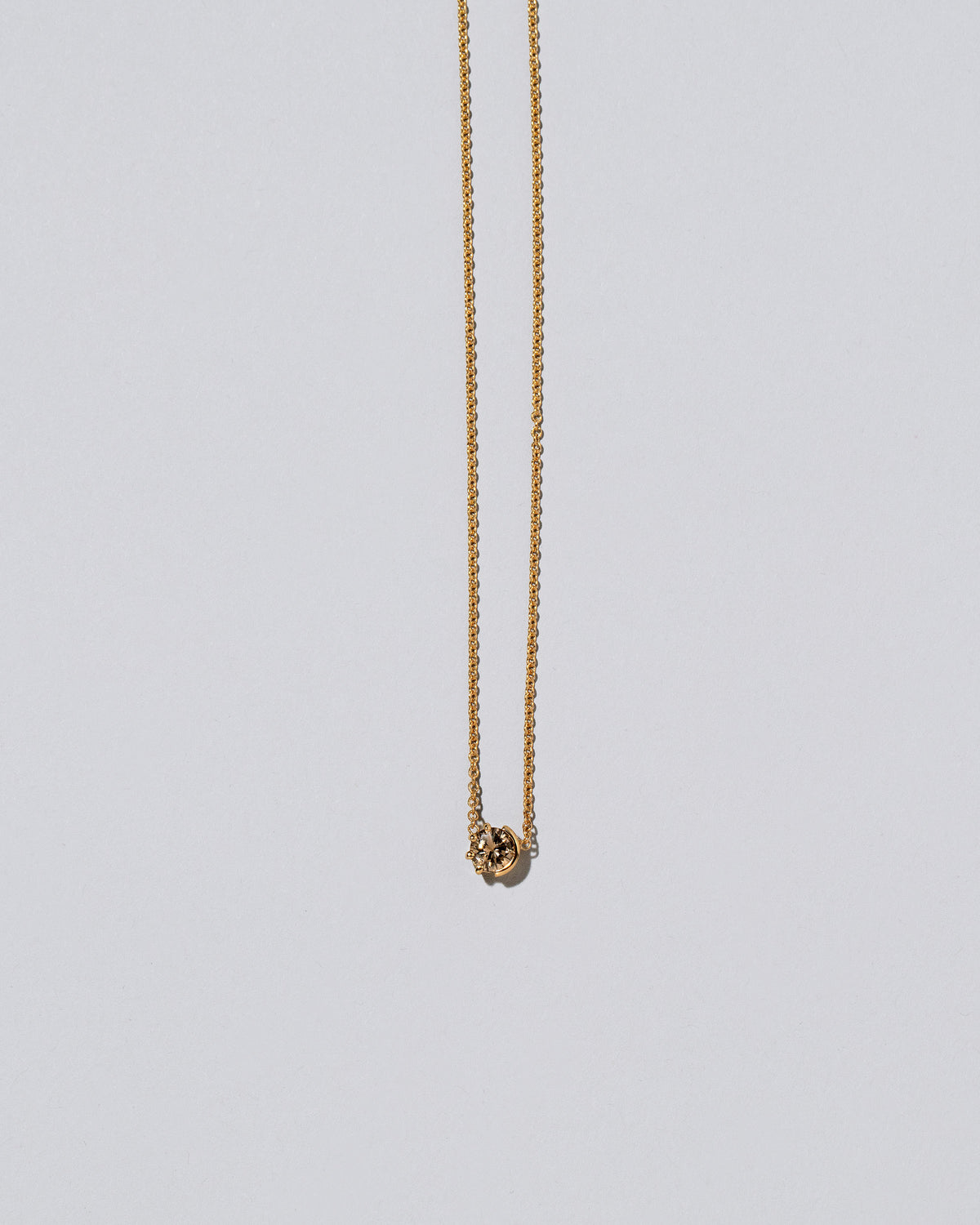 Closeup view of the Champagne Diamond Sun & Moon Necklace on light color background.