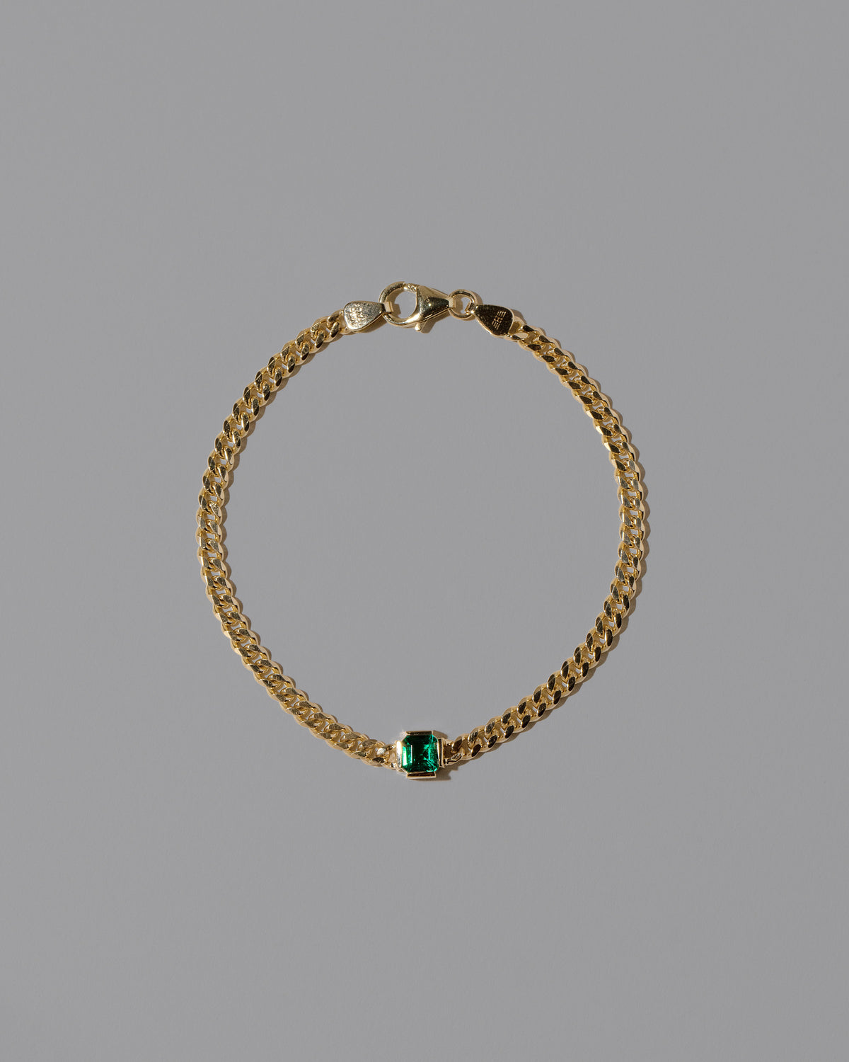 Gold Emerald Fold Bracelet on light color background.