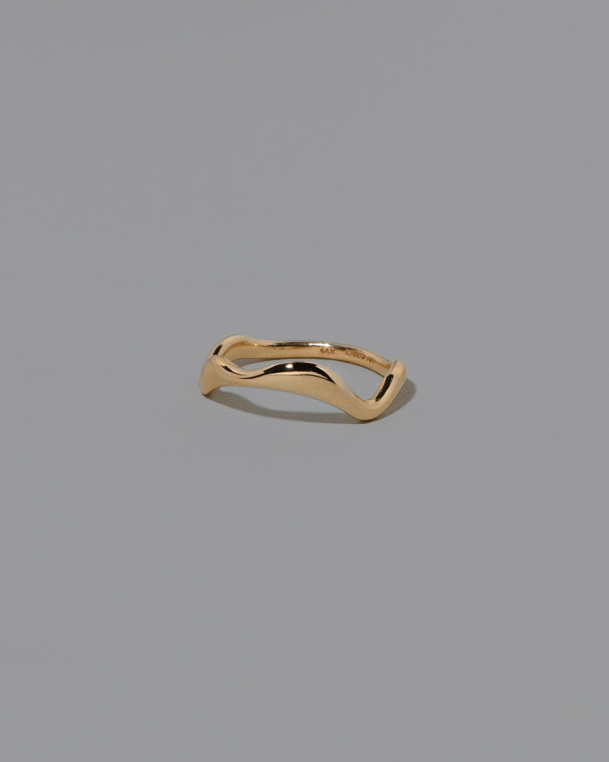 View from the side of the Gold Thin Fluctuating Band on light color background.