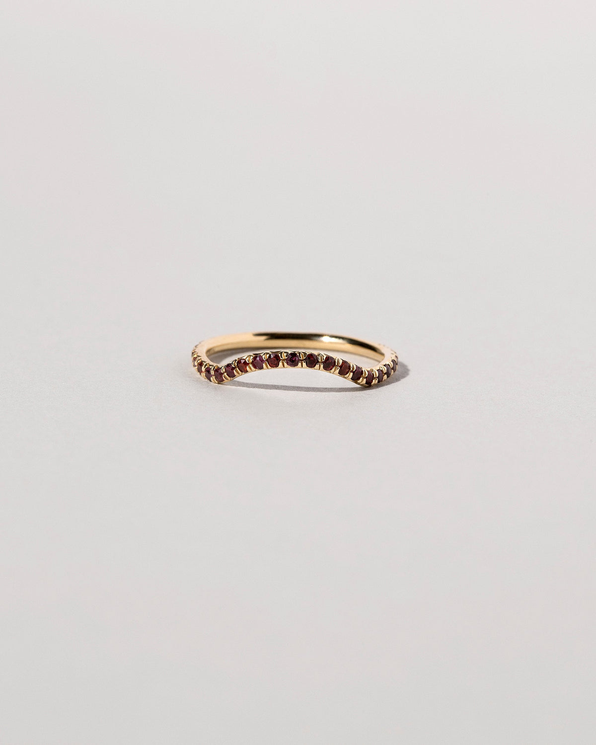 Gold Garnet Pavé Mini Curve Band on light color background.