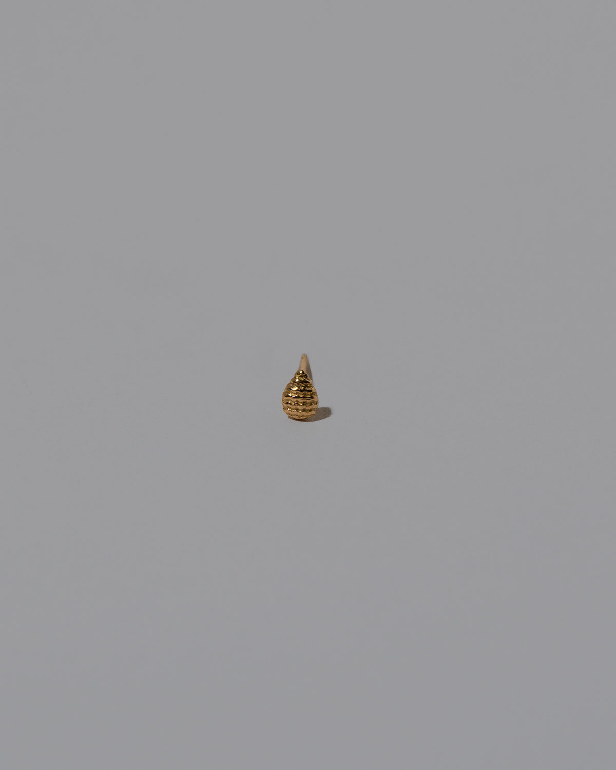 Closeup details of the Tear Stud Earring Single on light color background.