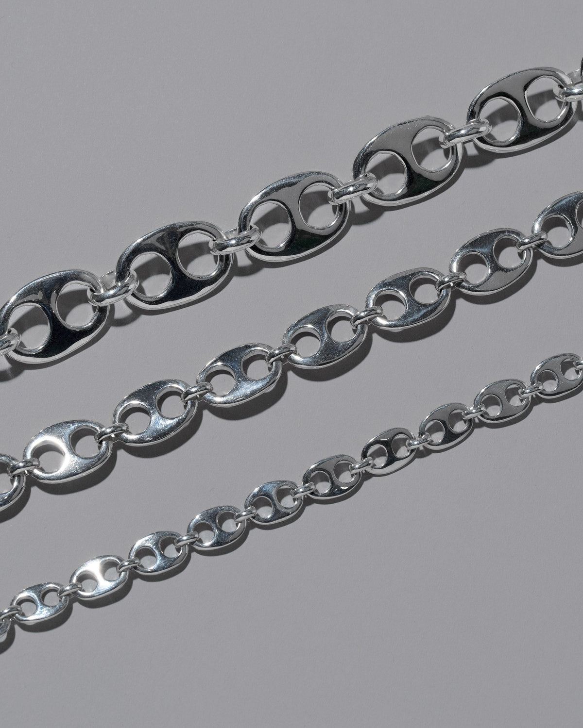 Closeup details of the CRZM Sterling Silver Yuba Mini Necklace, Sterling Silver Yuba Medium Necklace, and Sterling Silver Yuba Necklace on light color background.