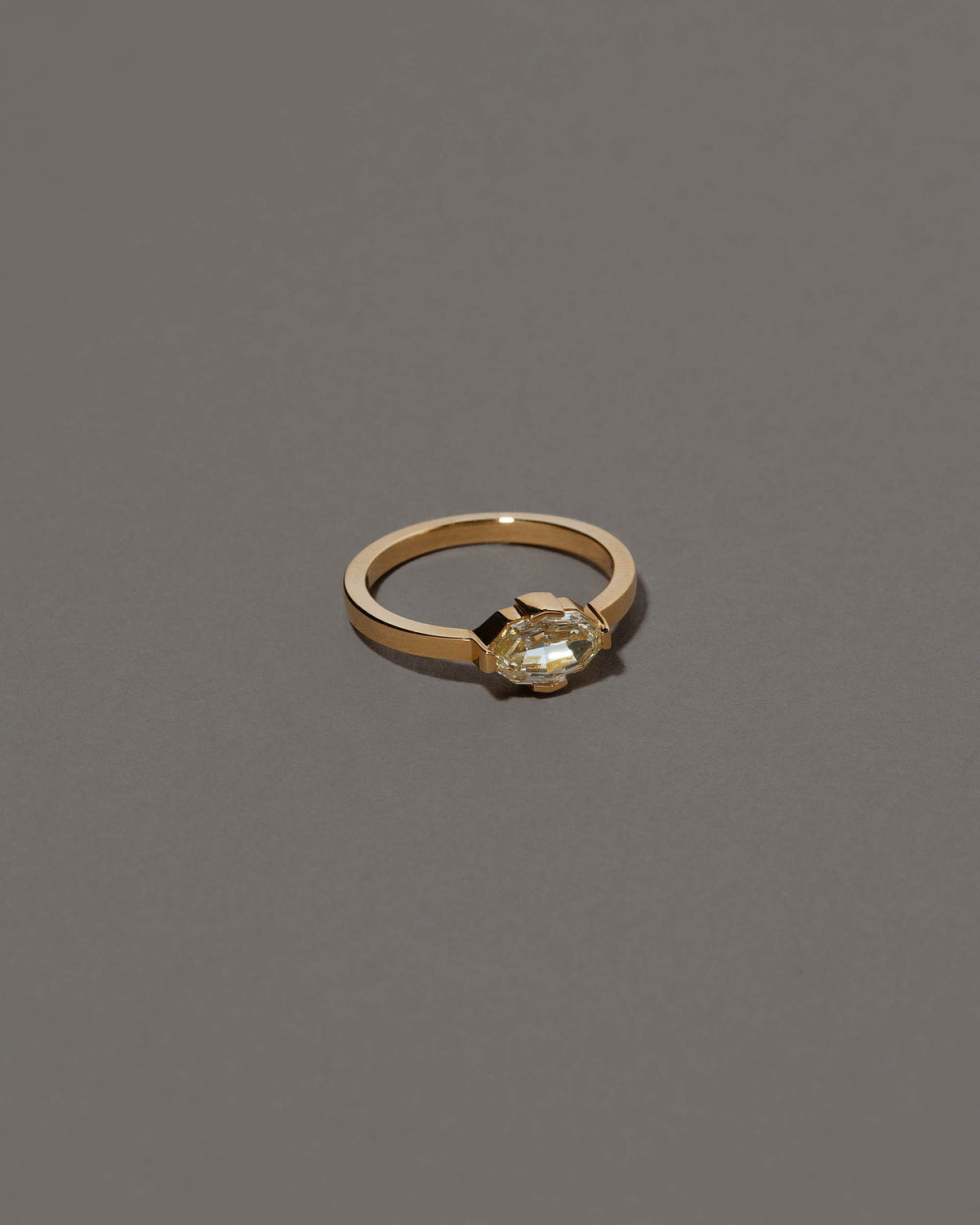 View from the side of the Beholden Ring on grey color background.