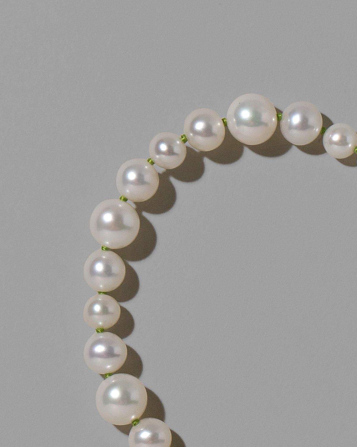 Closeup details of the Grass Green Thread Bubble Pearl Necklace on light color background.