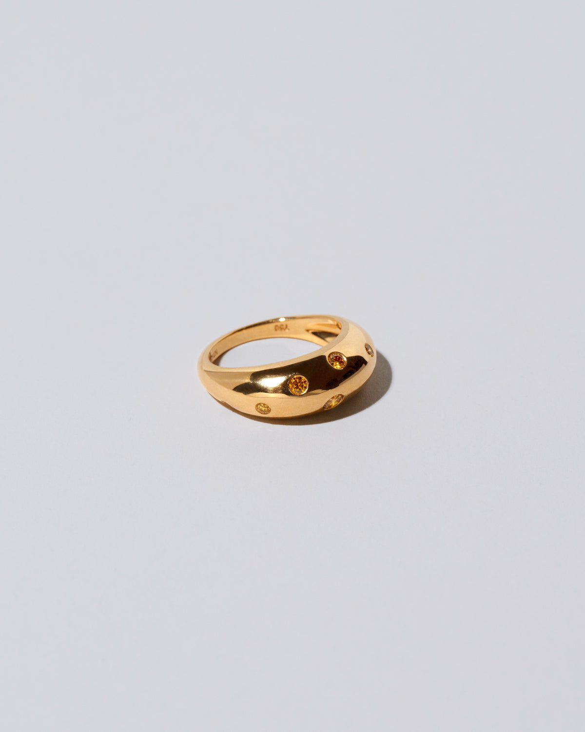 View from the side of the Gold Yellow Diamond Brilliant Cuts Light Cutter Band on light color background.
