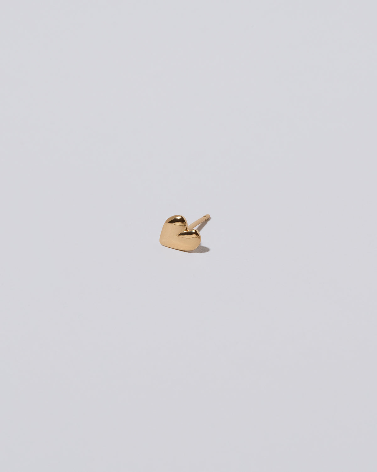 View from the side of the Shape One Small Thousand & One Night Heart Stud Earring single on light color background.