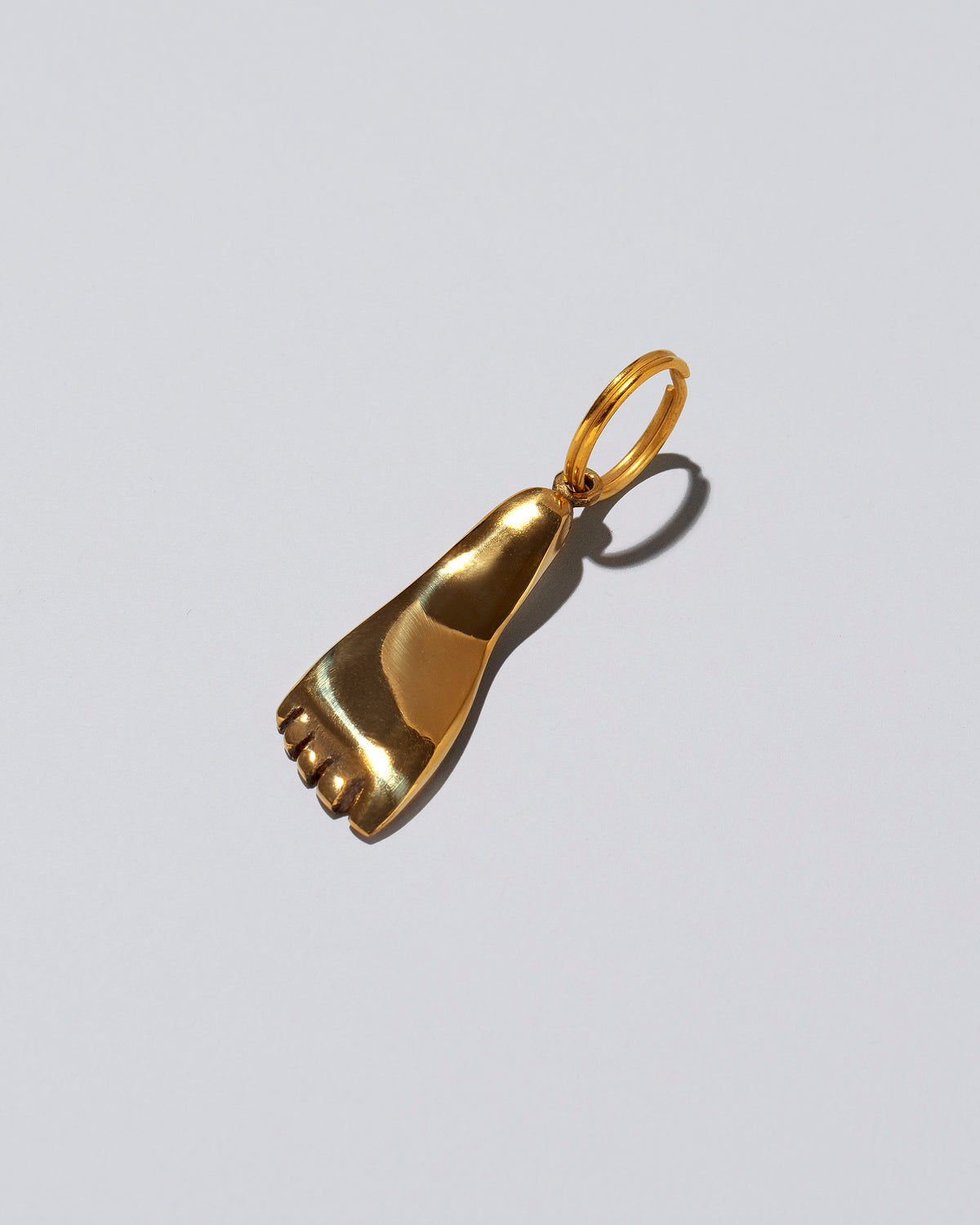 View from the side of the Carl Auböck Brass Foot Keyring on light color background.