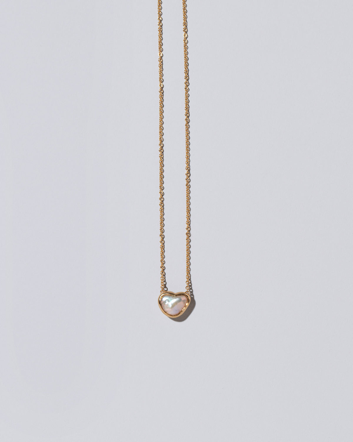 Closeup detail of the Lunar Heart Necklace on light color background.