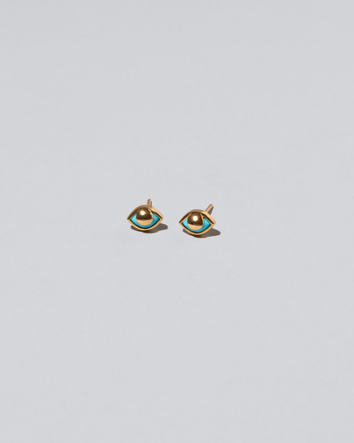 Gold Eye See You Stud Earrings on light color background.