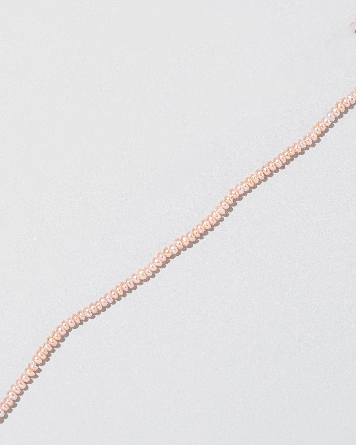 Closeup details of the Pink Peony Pebble Seed Pearl Choker Necklace on light color background.