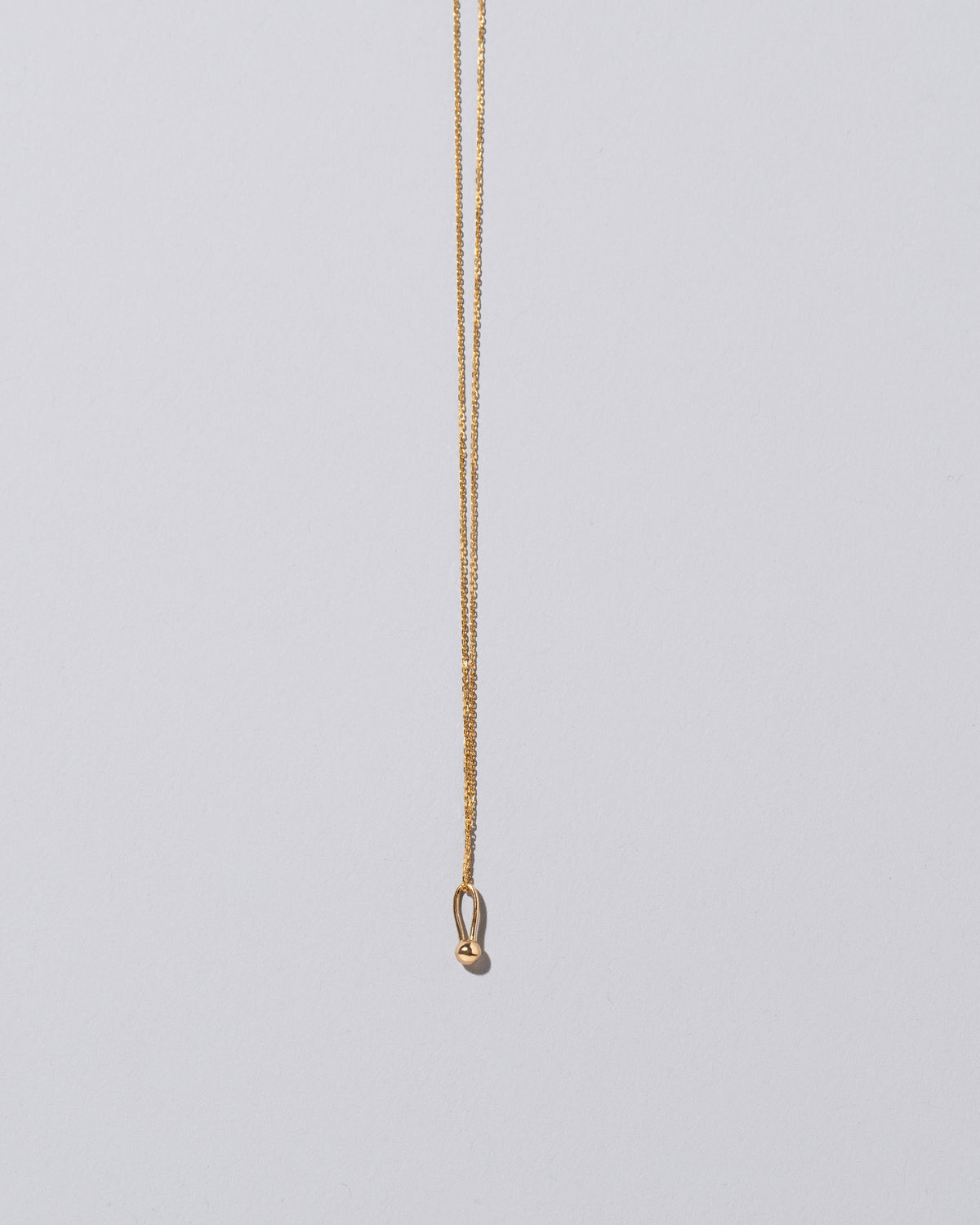 Loop & Sphere Talisman Pendant Necklace on light color background.