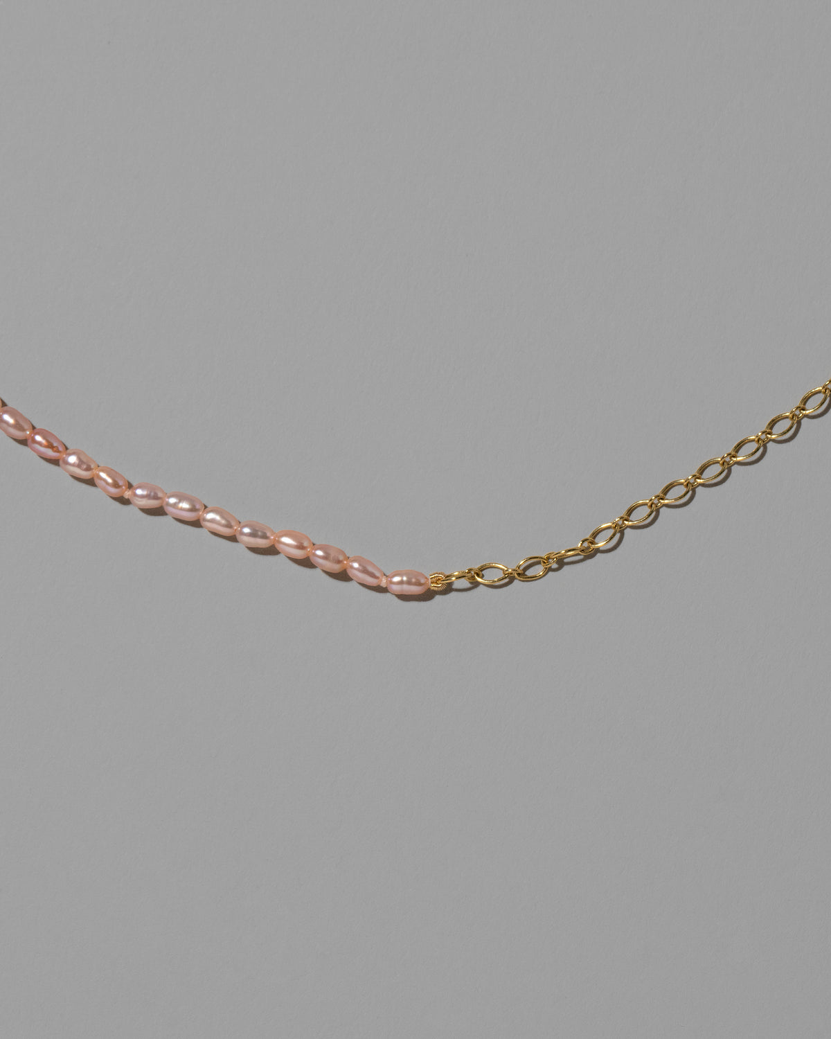 Closeup details of the Half Oval Chain & Peony Seed Pearl Necklace on light color background.