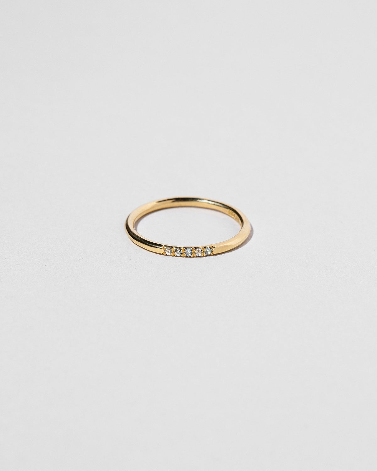 Gold Five Stone Blue Sapphire Dot Band on light color background.