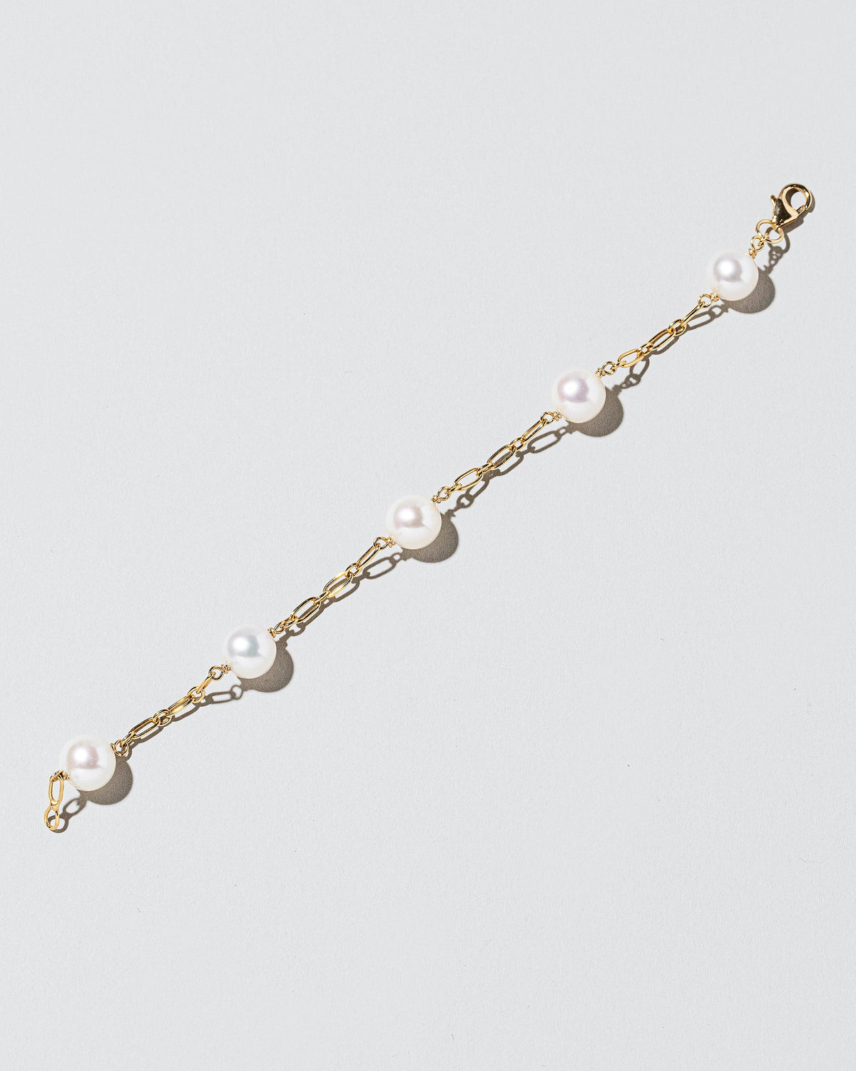 Five Pearl Station Bracelet Hot Dog Chain on light color background.