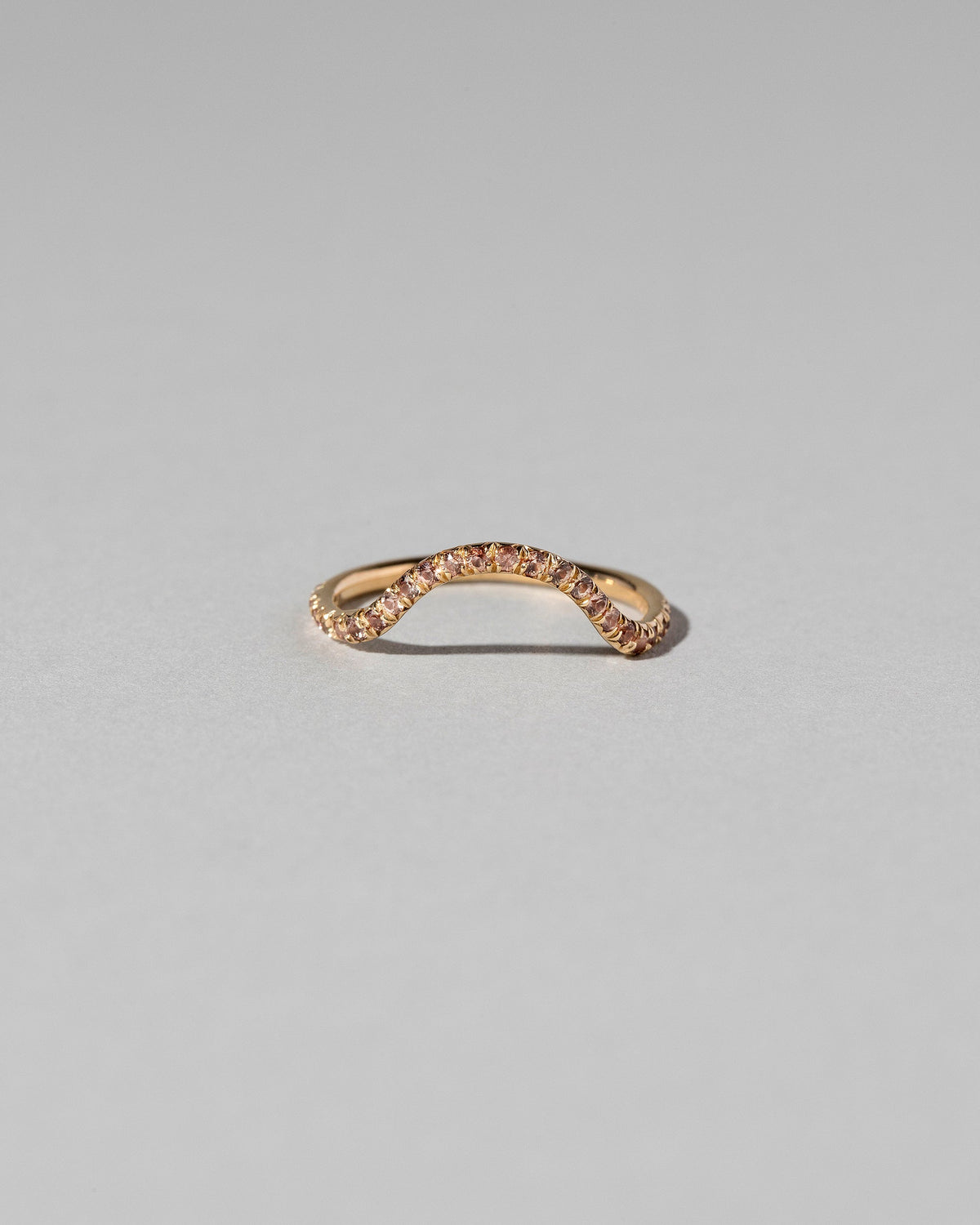 Gold Pavé Peach Sapphire Curve Band on light color background.