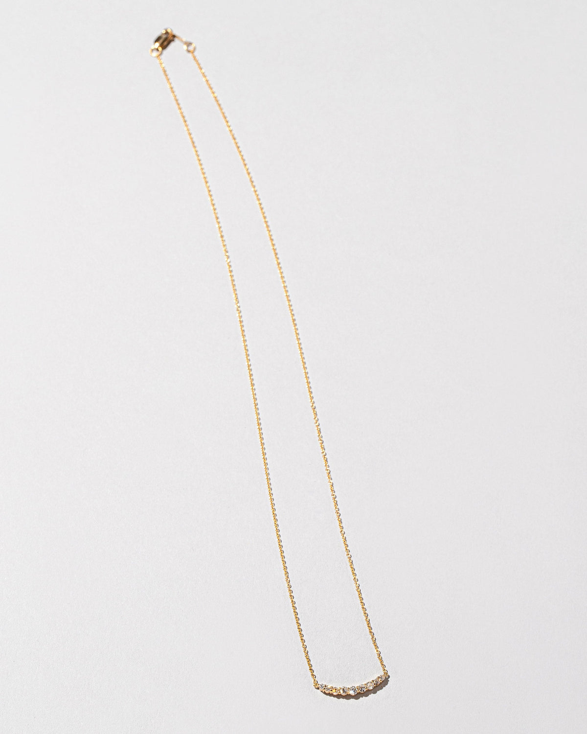 White Diamond Crescent Necklace on light color background.