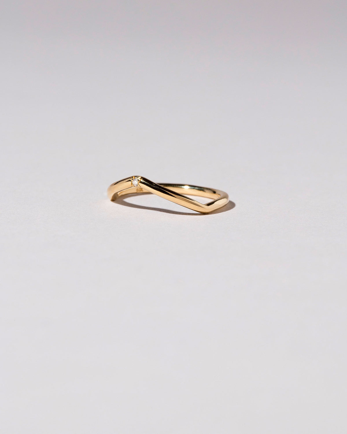 Gold Single Stone White Diamond Low Peak Band on light color background.