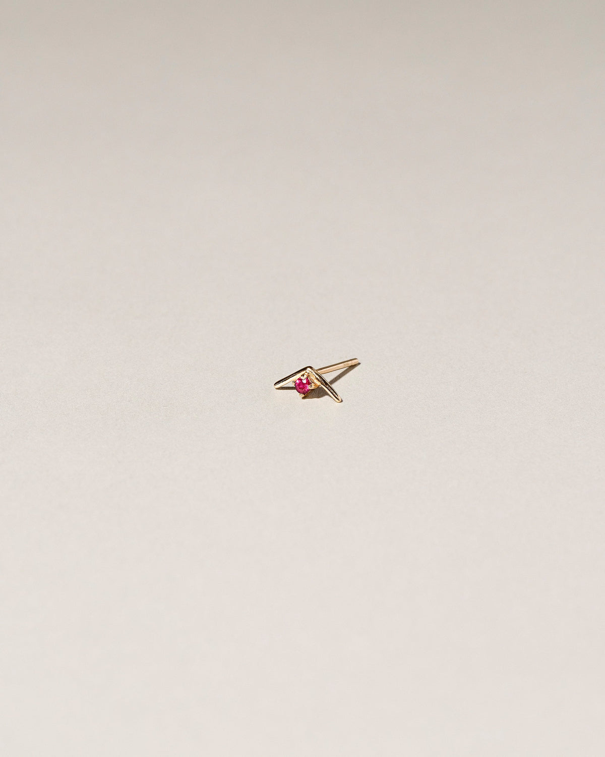 Gold Ruby Sun Catcher Stud Earring Single on light color background.