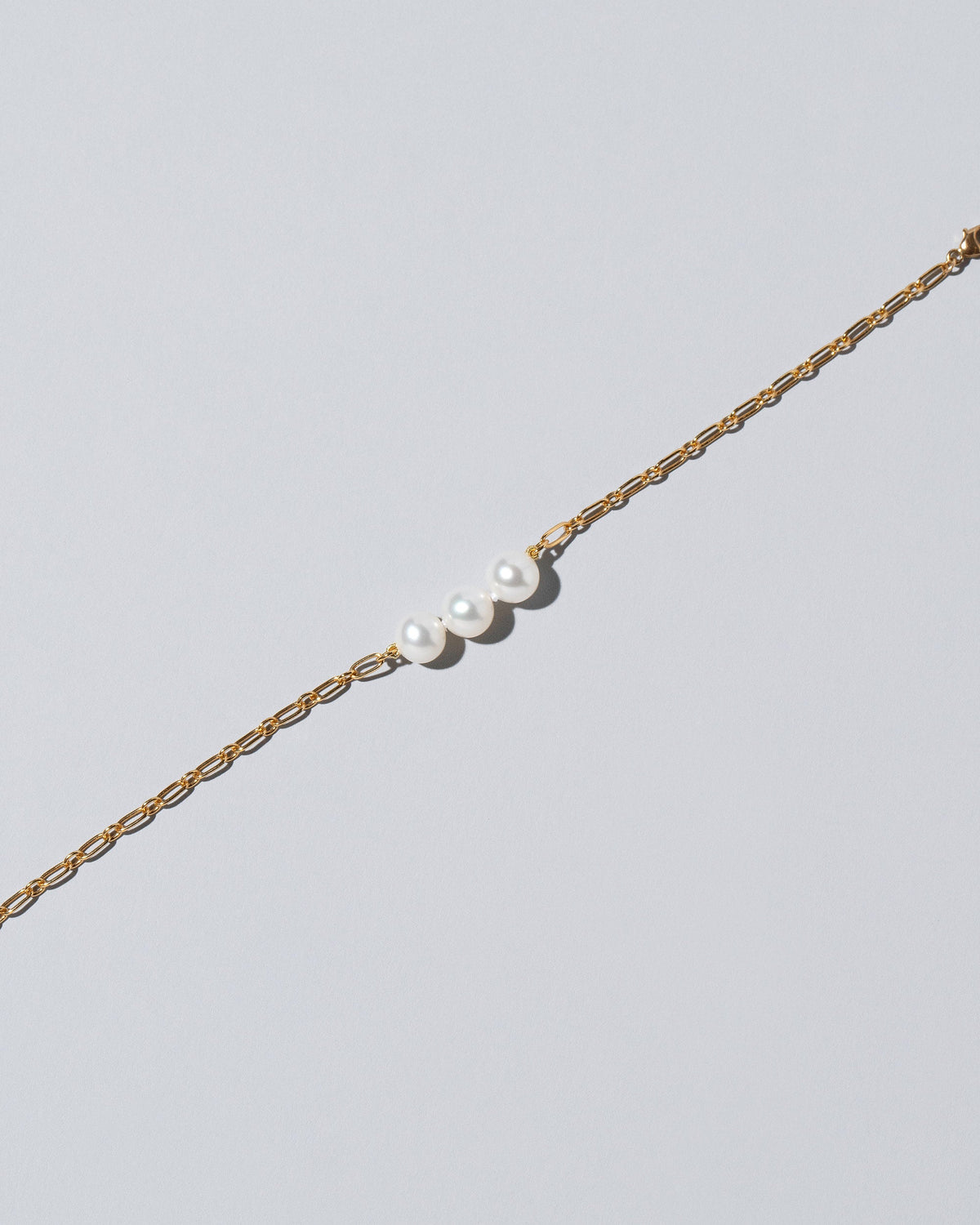 Closeup details of the Three Pearl Station Bracelet Hot Dog Chain on light color background.