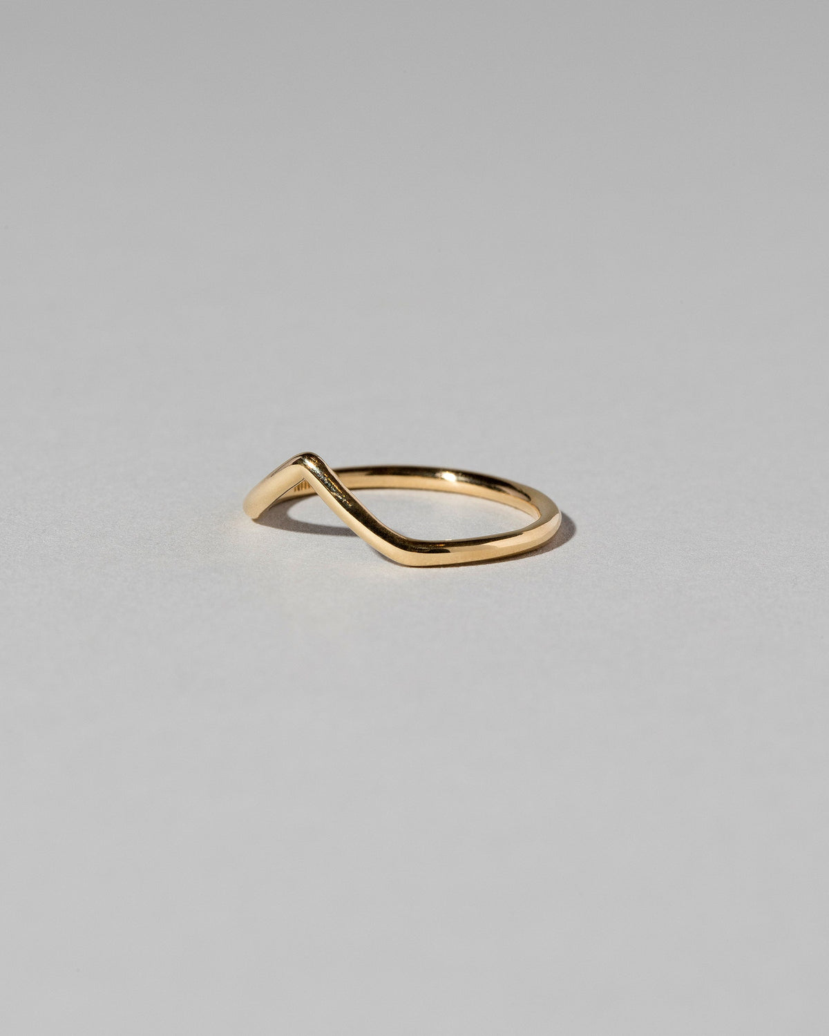View from the side of the Gold Solid Round Wire High Peak Band on light color background.