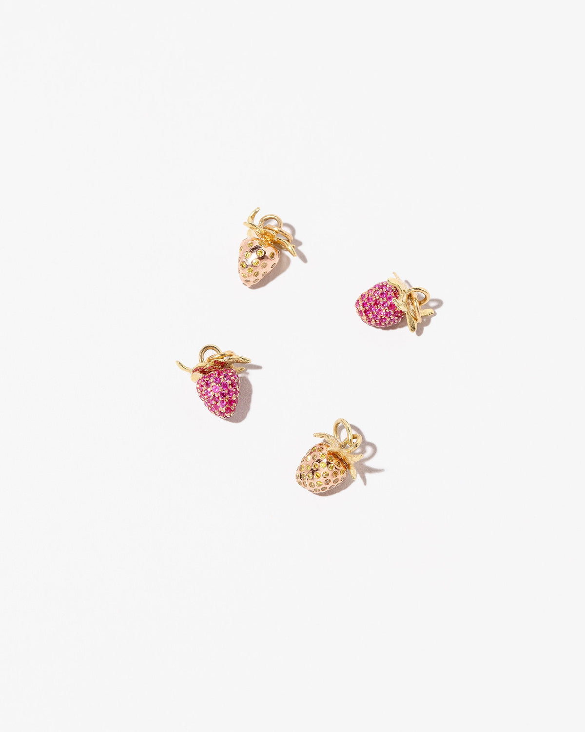 Wild Strawberry Charm, Diamond & Ruby Pavé Strawberry Charm and Ruby Pavé Strawberry Charm on light color background.