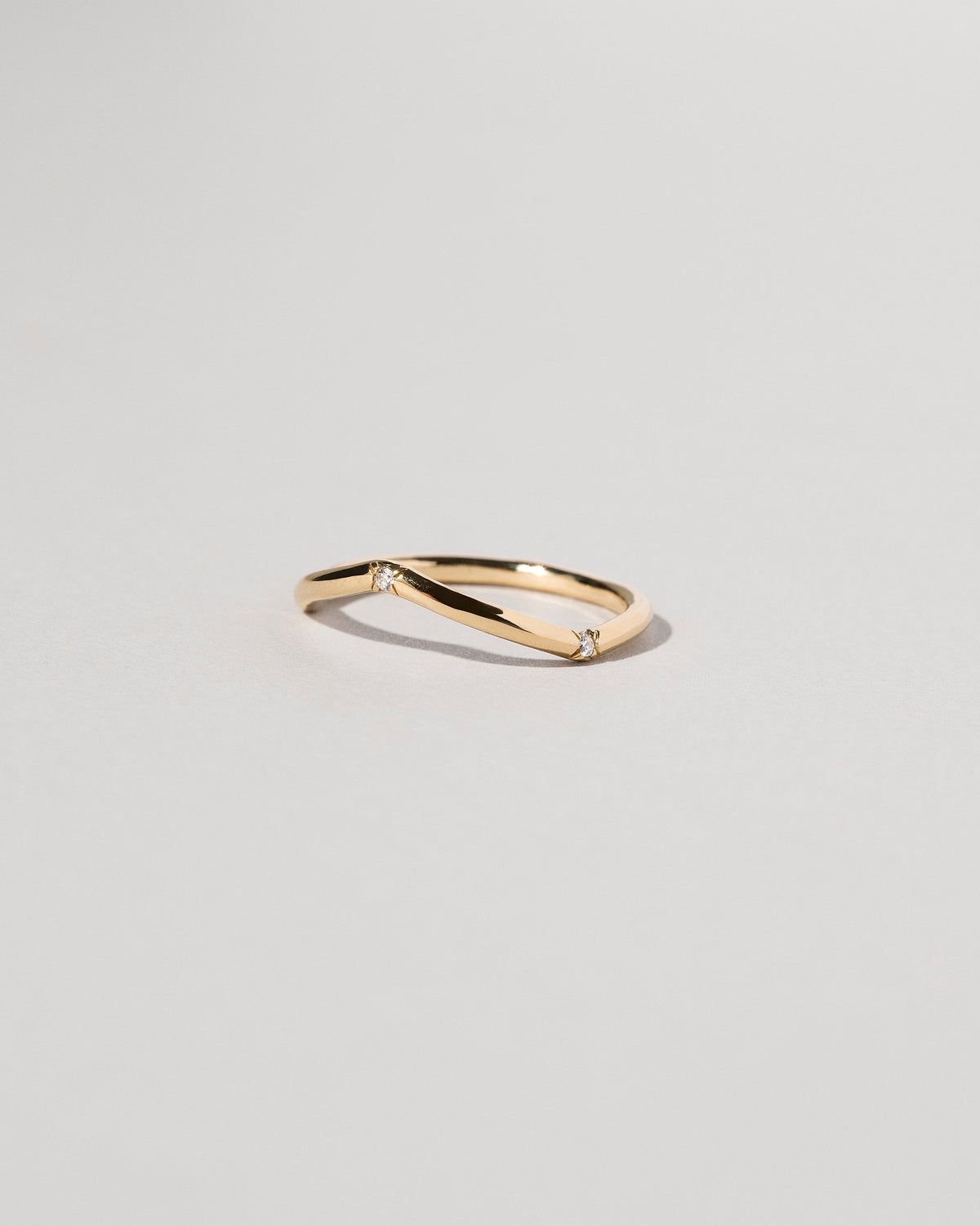 View from the side of the Gold Three Stone White Diamond Low Peak Band on light color background.