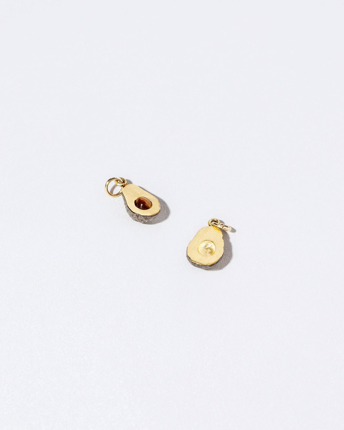 Closeup details of the Halved Avocado Charms on light color background.