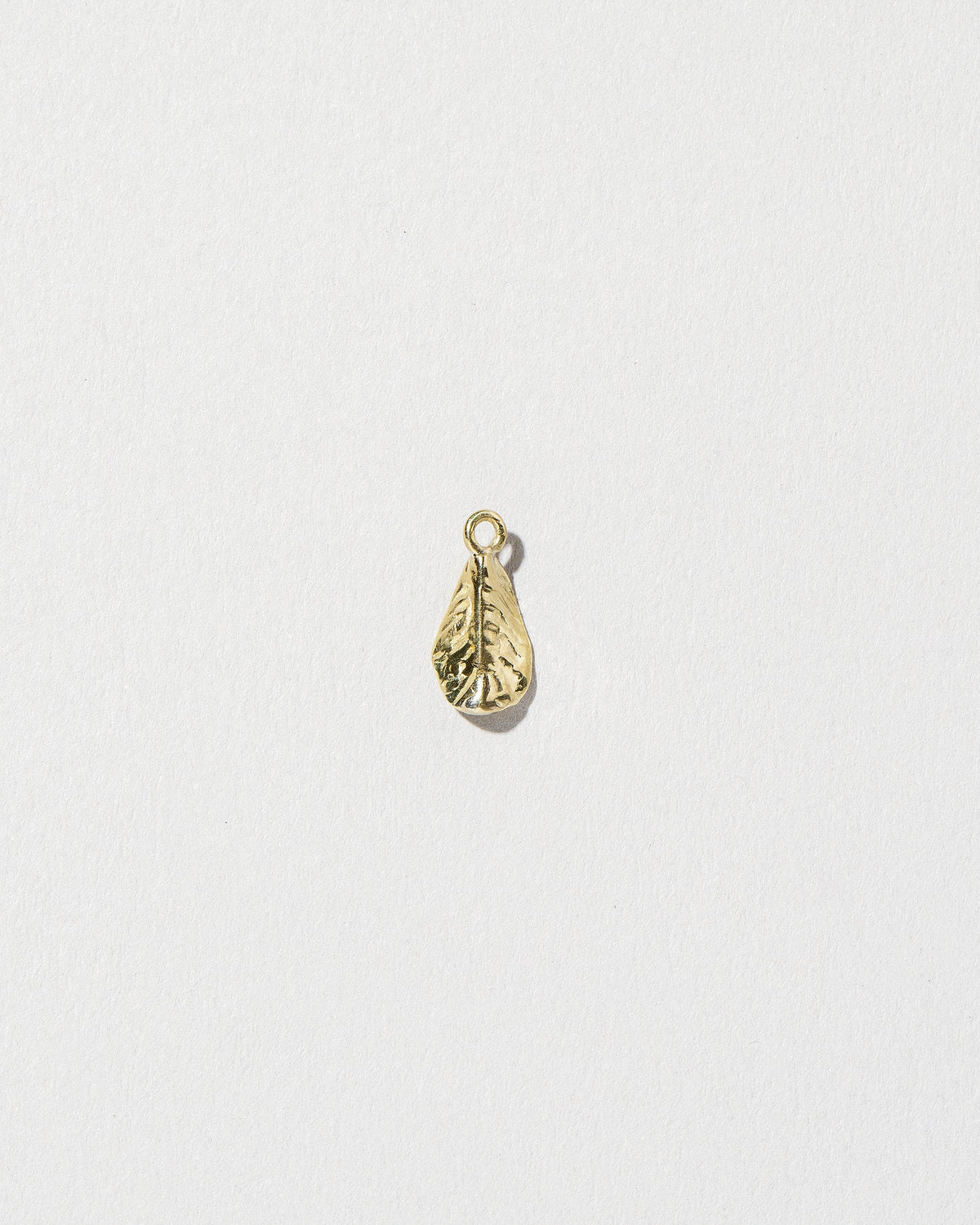 View from the back of the #5 Arugula Charm on light color background.