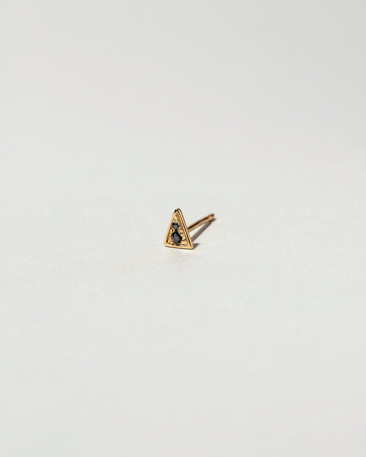 Gold Black Diamond Triangle Stud Earring Single on light color background.