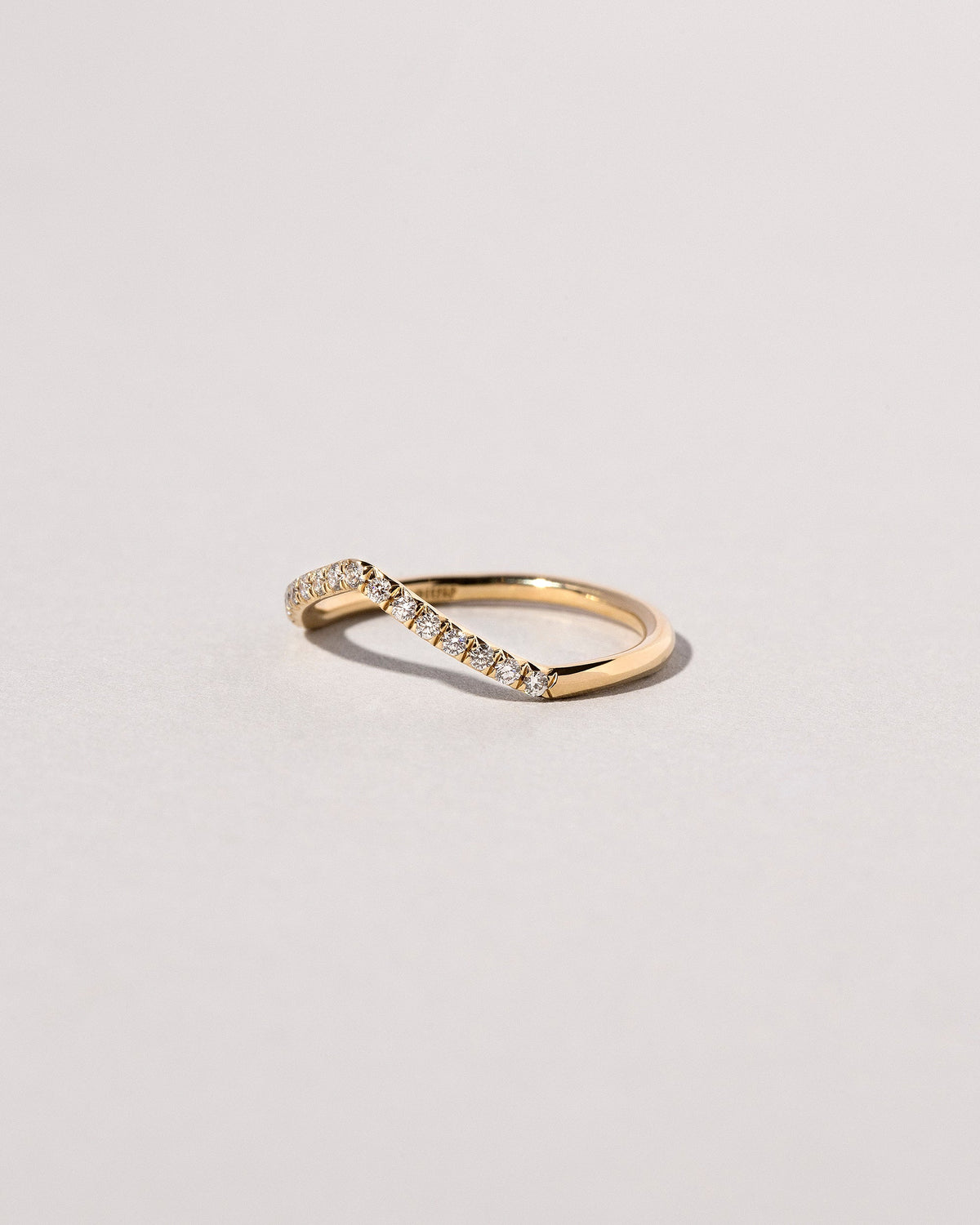 View from the side of the Gold Pavé White Diamond Low Peak Band on light color background.