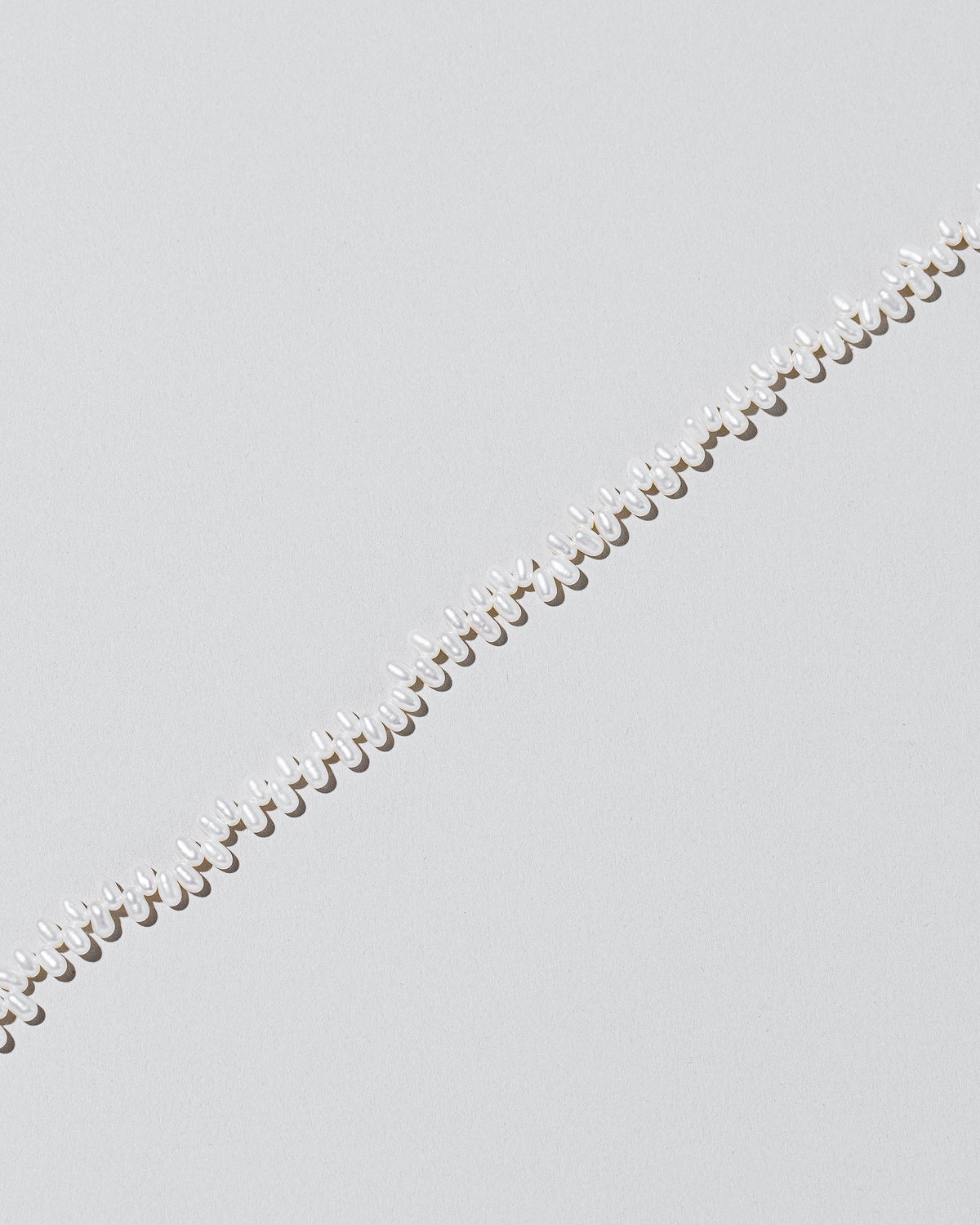 Closeup details of the Small Zipper Pearl Necklace on light color background.