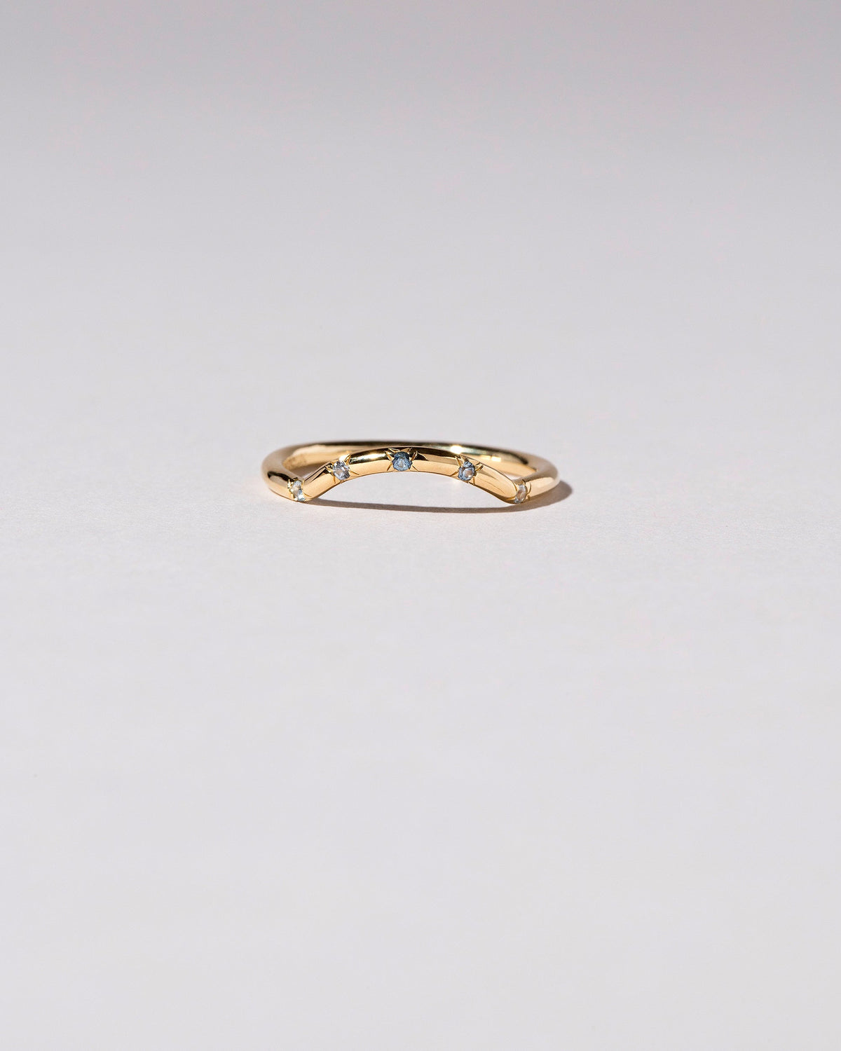 Gold Five Stone Blue Sapphire Mini Curve Band on light color background.