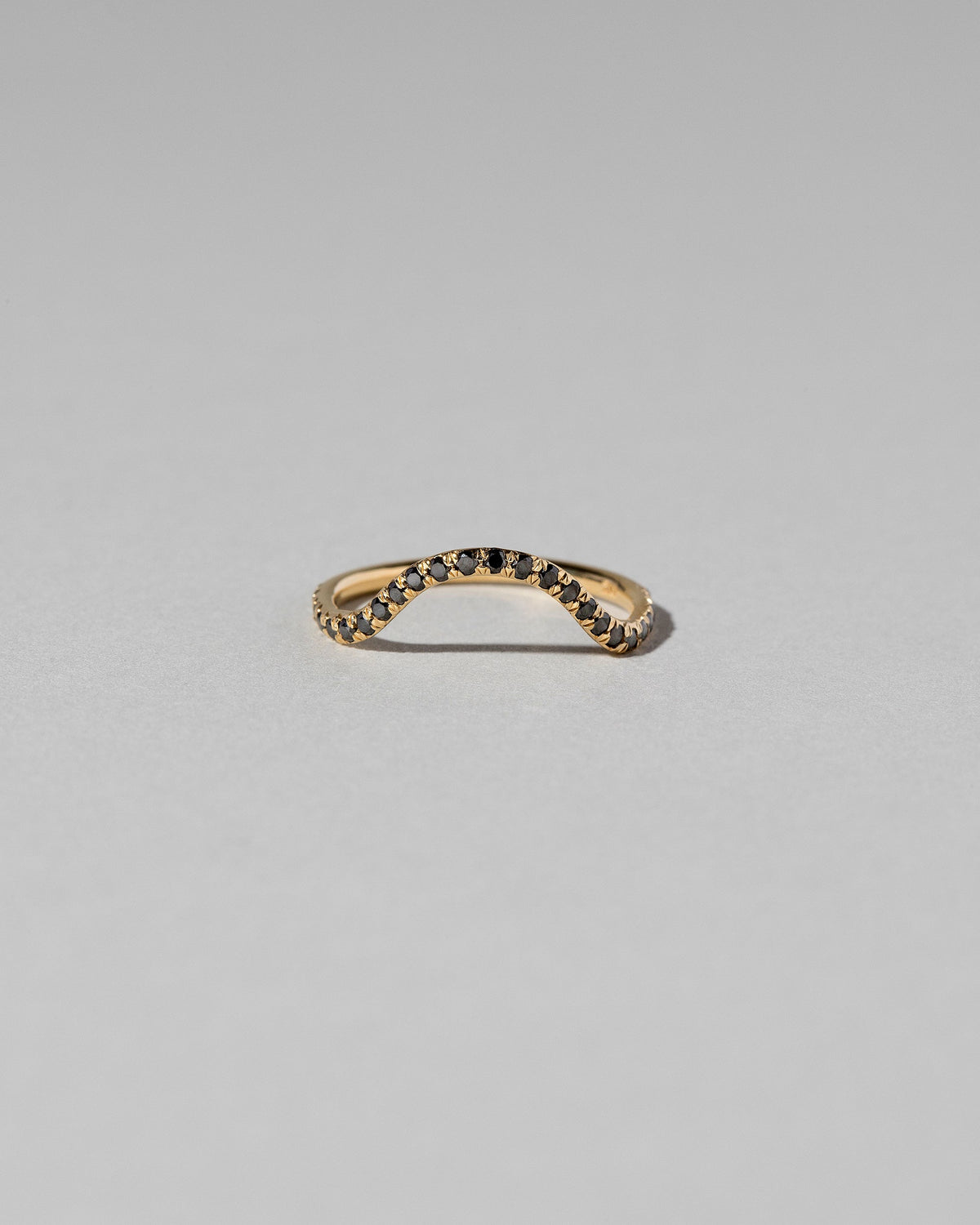 Gold Pavé Black Diamond Curve Band on light color background.