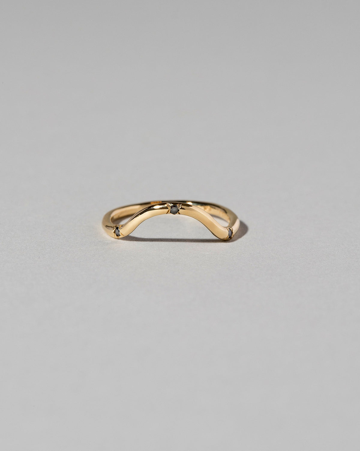 Gold Three Stone Black Diamond Curve Band on light color background.