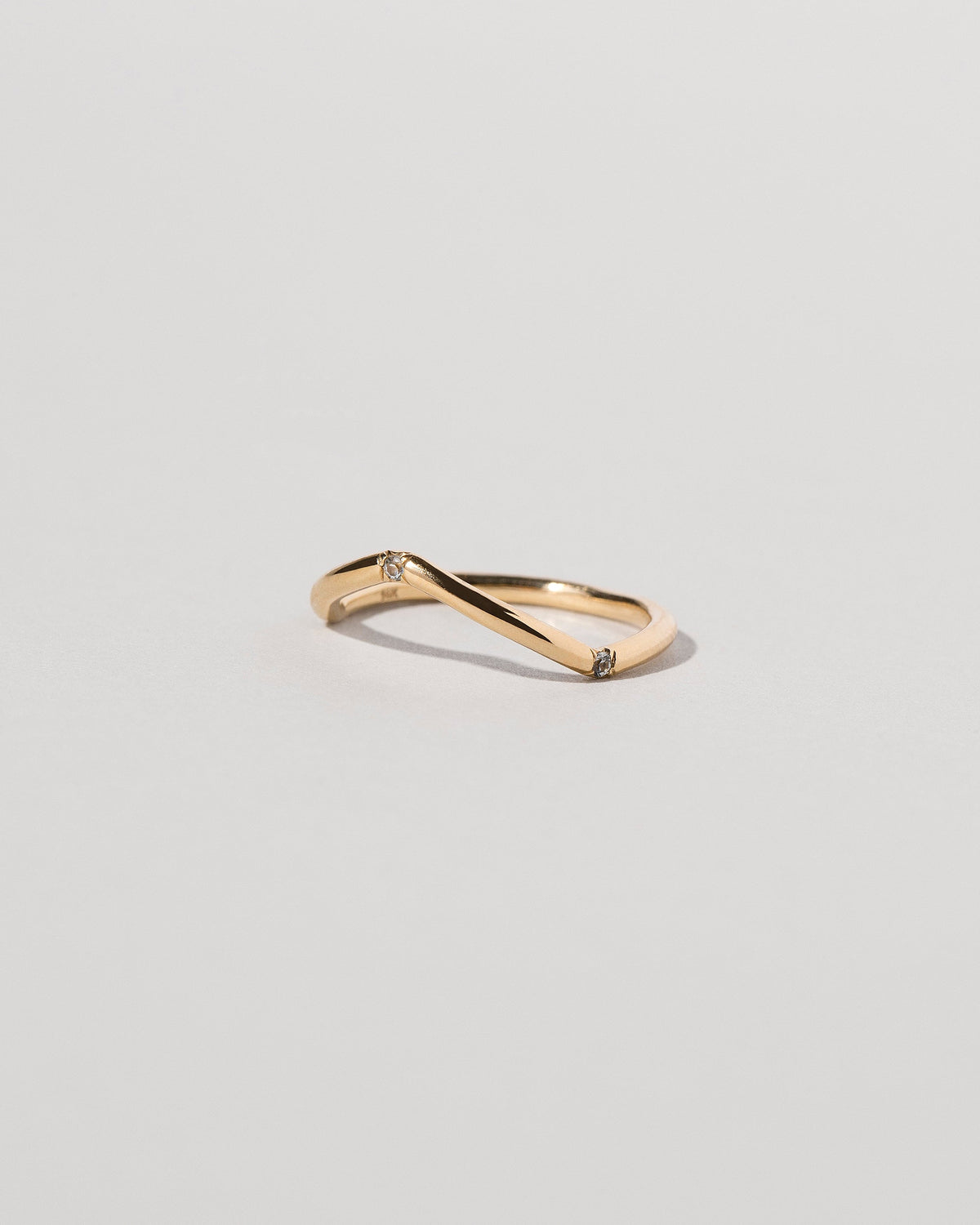 View from the side of the Gold Three Stone Blue Sapphire Low Peak Band on light color background.