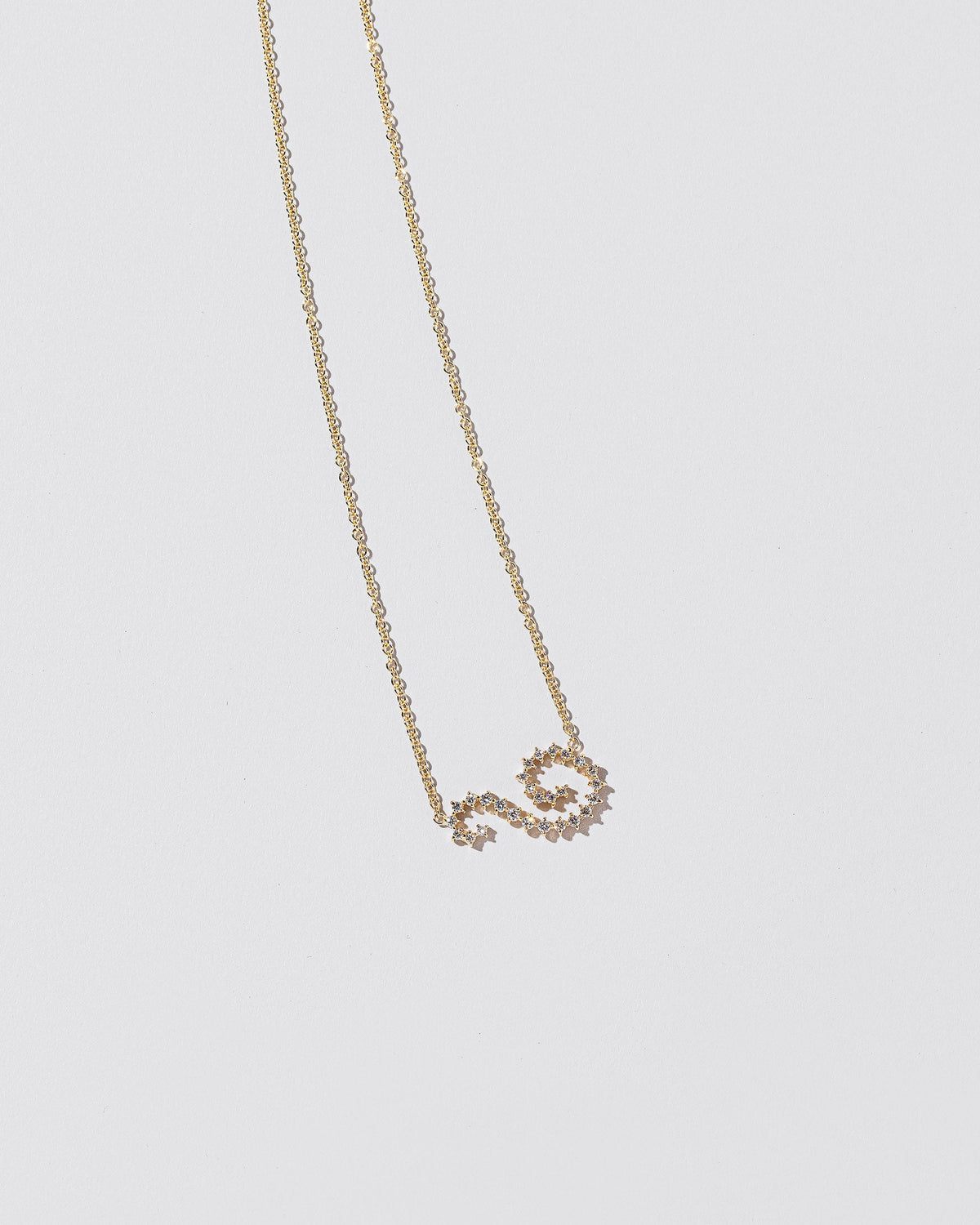 White Diamond Symbol of Change Necklace on light color background.