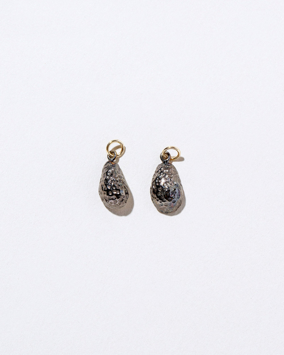 View from the back of the Halved Avocado Charms on light color background.