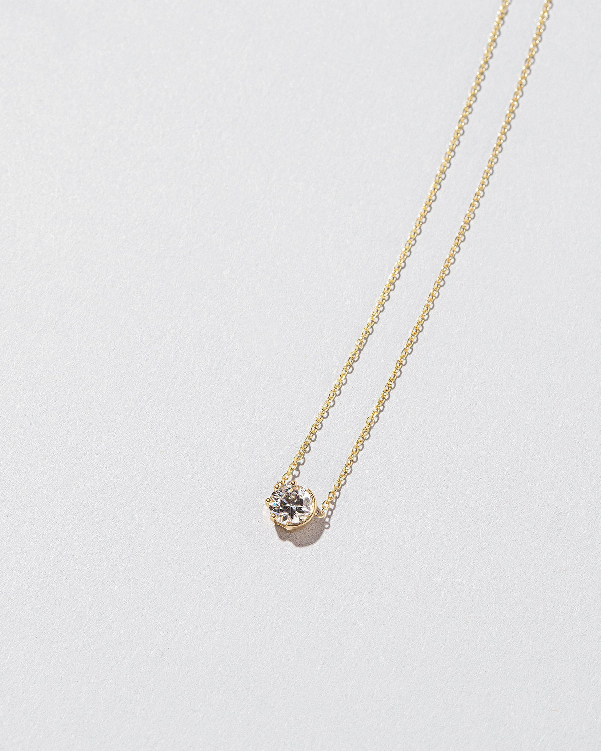 White Diamond Sun & Moon Necklace on light color background.