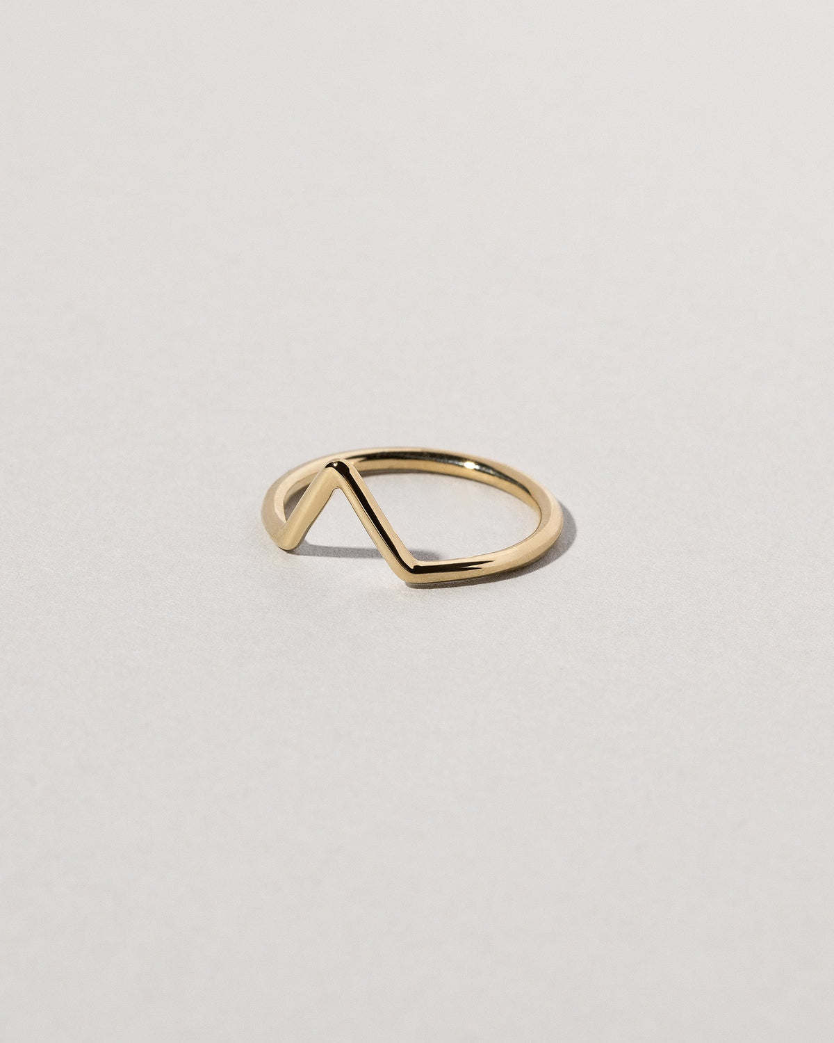 View from the side of the Gold Solid Round Wire Triangle Band on light color background.