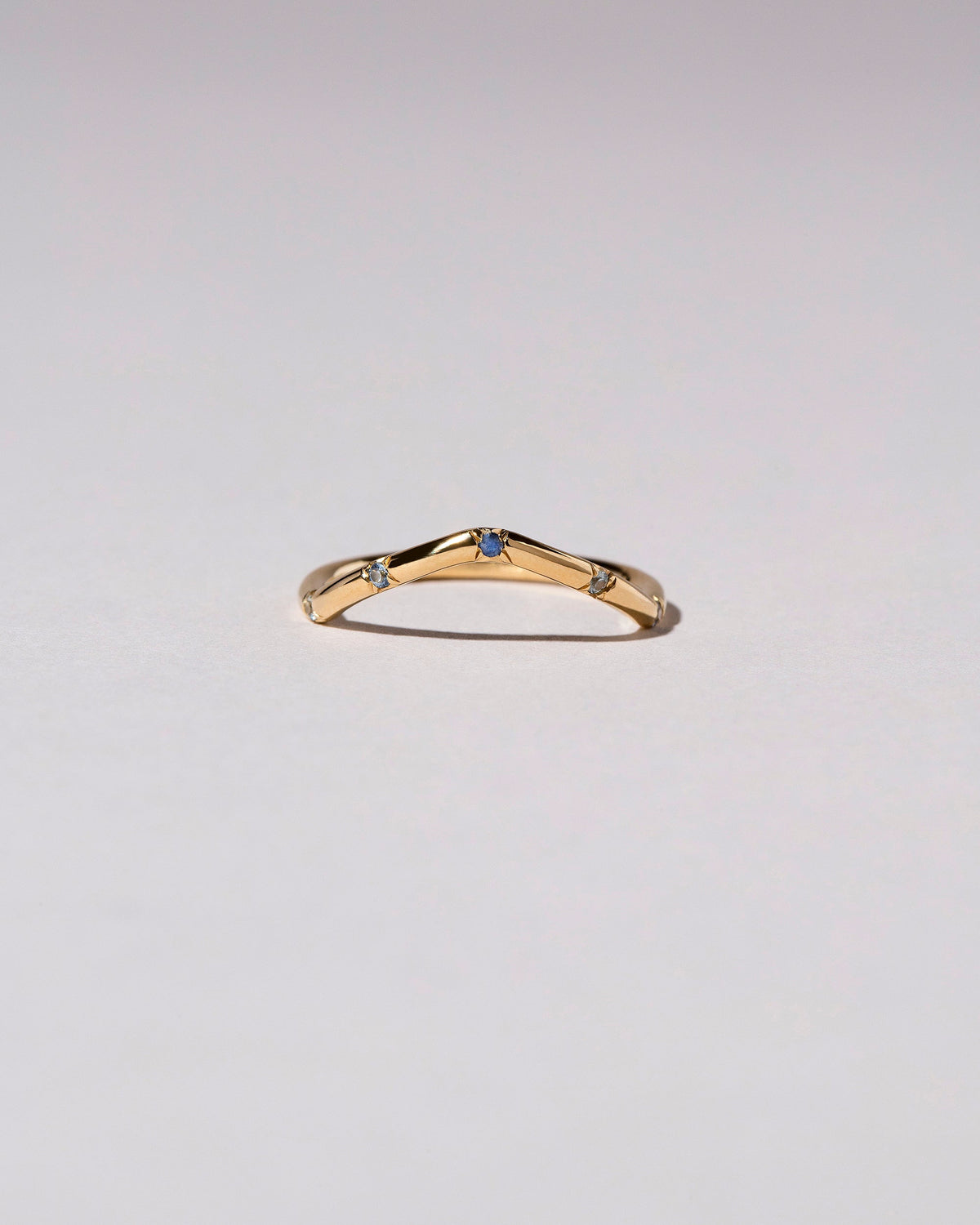 Gold Blue Sapphire Five Stone Low Peak Band on light color background.