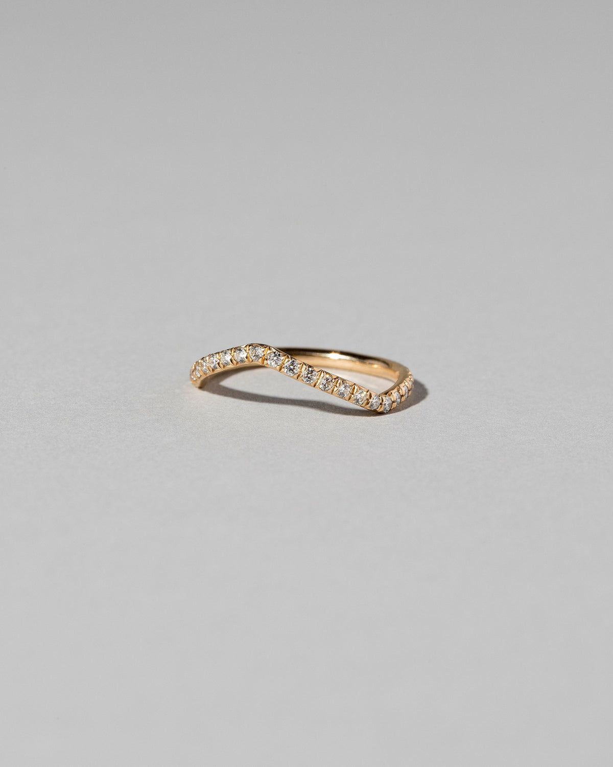 View from the side of the Gold Pavé White Diamond Low Peak Band on light color background.