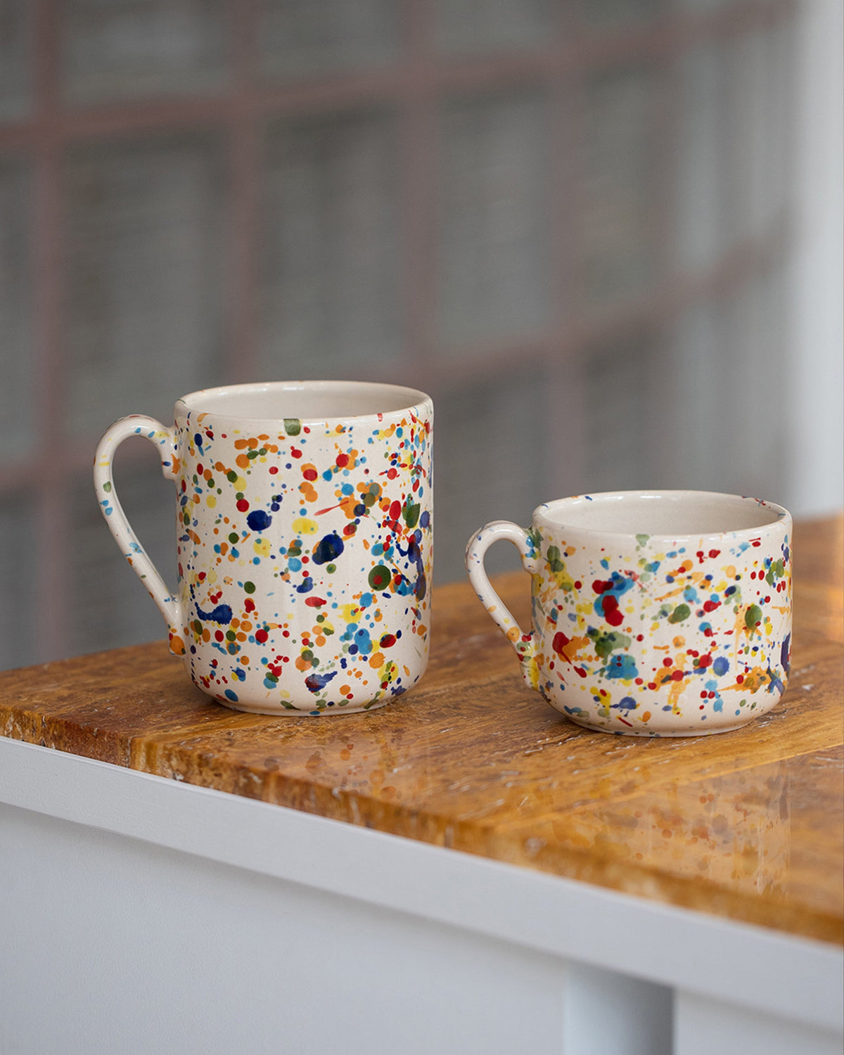 Styled image featuring the La Ceramica Vincenzo Del Monaco Colored Drops Coffee Mug and Colored Drops Tea Mug on light color background.