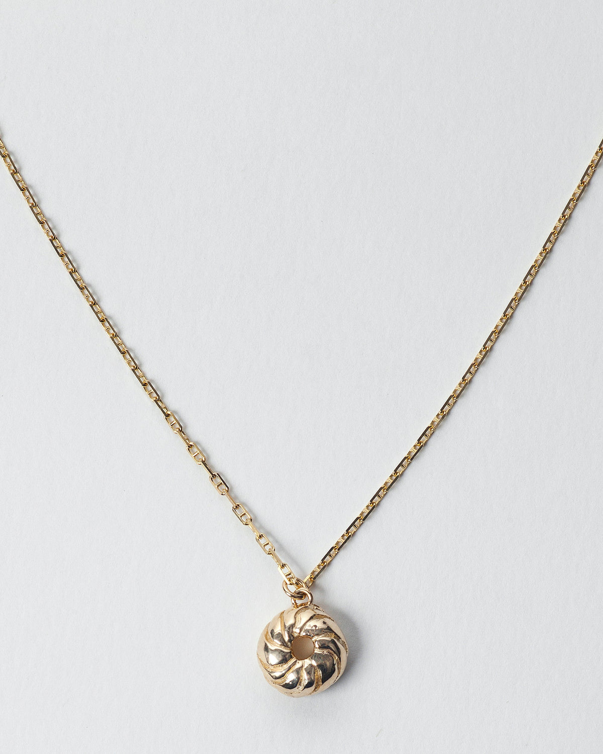  French Cruller Charm on chain, on light color background.