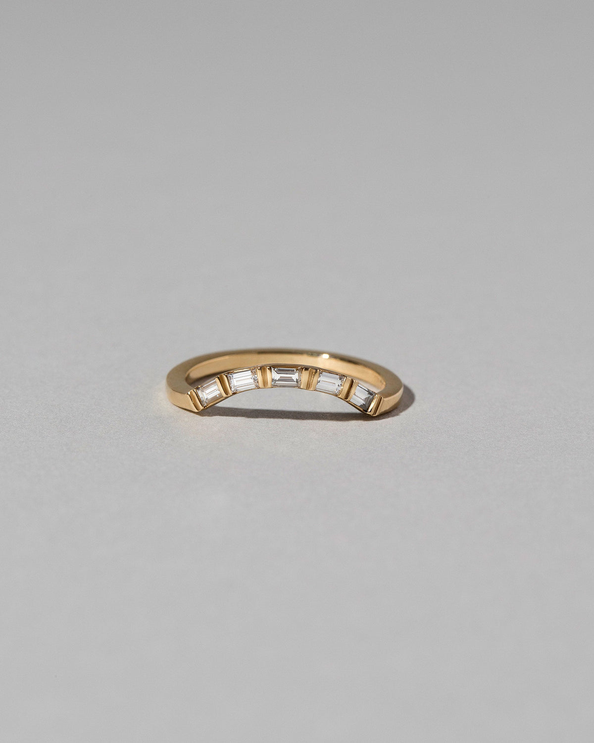 Gold Baguette Mini Curve Band on light color background.