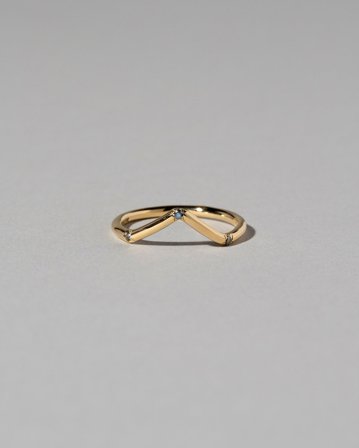 Gold Three Stone Blue Sapphire High Peak Band on light color background.