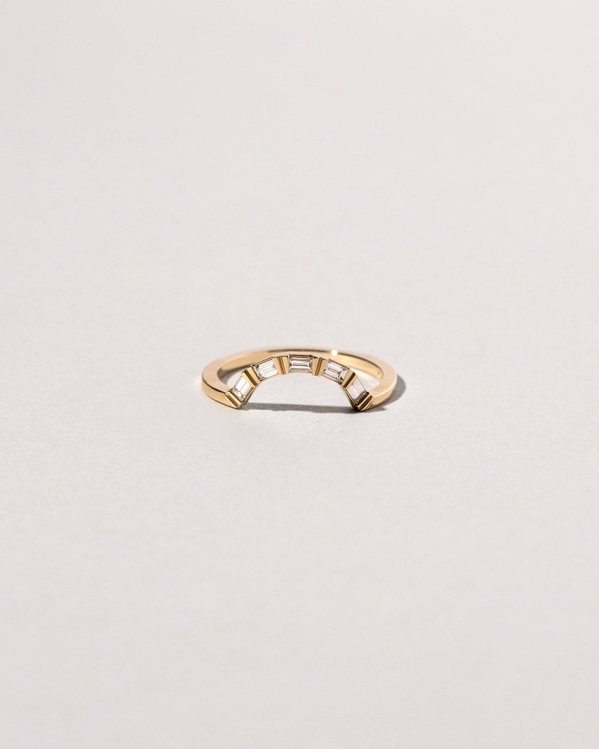 Gold Baguette Curve Band on light color background.